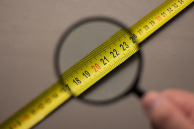 Tape measure seen through magnifying glass held by hand