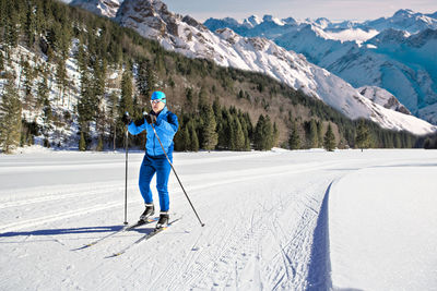 Full length of man skiing on snow against snowcapped mountains