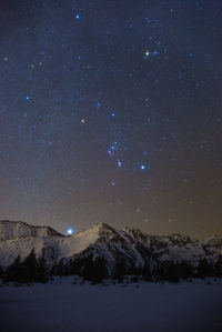 Scenic view of snowcapped mountains against sky at night