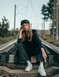 Young woman sitting on railroad track