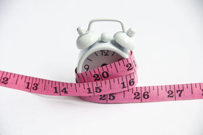 Fitness and weight loss concept - alarm clock tied with measuring tape.