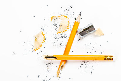 High angle view of broken colored pencils on white background