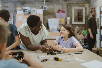 Happy student and teacher interacting with each other at technology workshop in school