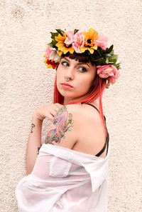 Portrait of young woman standing against wall