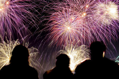 Silhouette people watching firework display at night