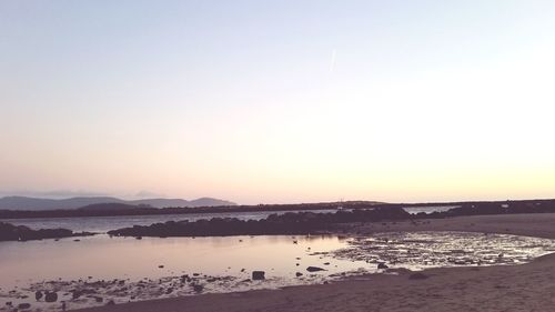 Scenic view of beach against clear sky during sunset