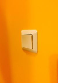 Close-up of light switch on yellow wall