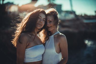 Portrait of smiling young women standing against sky