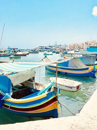 Boats moored at harbor against clear blue sky