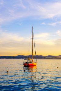 Sailboat sailing on sea against sky during sunset