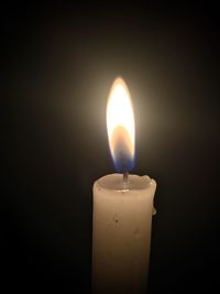 Close-up of lit candle against black background