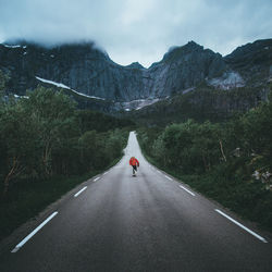 Man running on road amidst trees against mountains