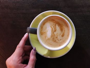 High angle view of woman holding coffee cup on table