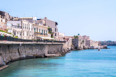 View of buildings by sea against clear sky