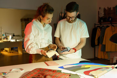 Dressmakers choosing cloth fabric for clothes collection. seamstress female talking to designer man