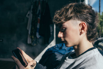 Stylish teenager boy texting with mobile phone