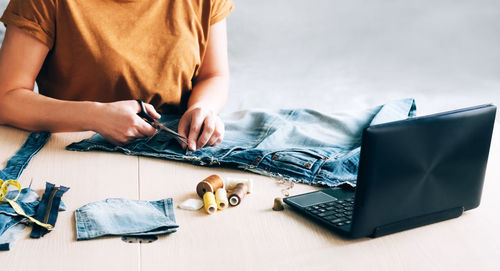 Midsection of man using mobile phone on table