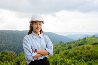 Portrait of young woman standing against sky