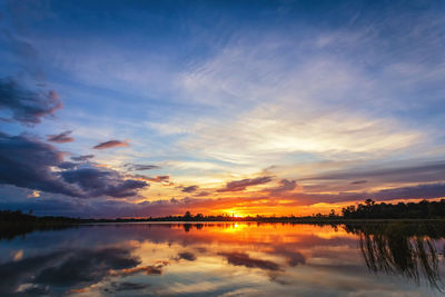 Scenic view of lake against dramatic sky during sunset