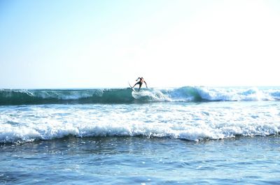 Man surfing in sea against clear sky