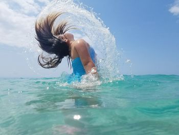 Side view of woman tossing hair in sea