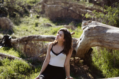 Woman looking away while sitting in forest