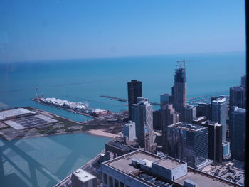 High angle view of buildings by sea against blue sky