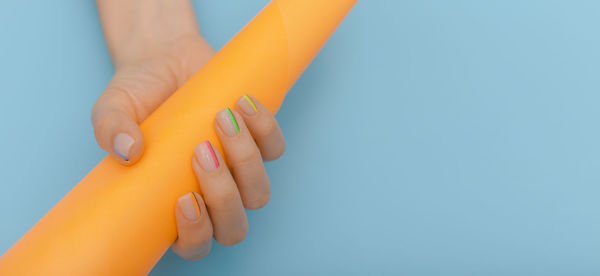 Close-up of woman hand holding yellow against blue background