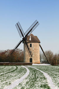 Traditional windmill on field against clear sky