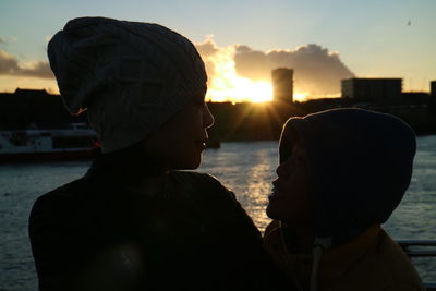 Close-up of sisters standing by thames river during sunset