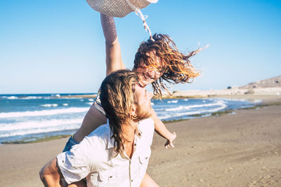 Midsection of woman at beach against sky