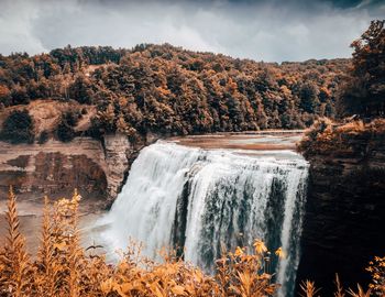 Scenic view of waterfall in forest against sky