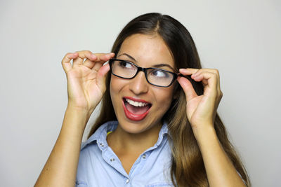 Close-up of cheerful woman wearing eyeglasses against gray background