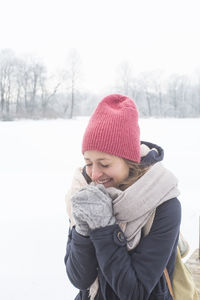 Woman wearing hat standing on field during winter