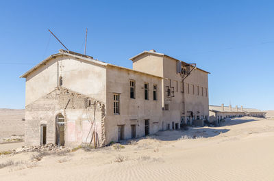 Abandoned building against clear blue sky at former german ghost town kolmanskop near luderitz, namibia