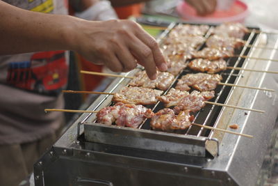 Close-up of man preparing food on barbecue grill