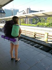Rear view of woman standing on railroad station platform