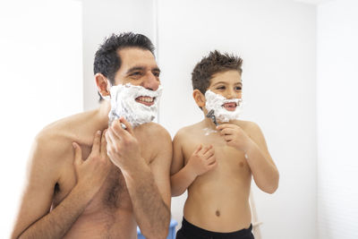 Funny father and son shaving in the bathroom