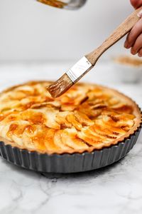 Close-up of hand applying honey on pie