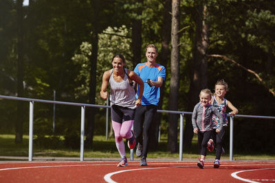 Parents with daughters running on running track  on the move