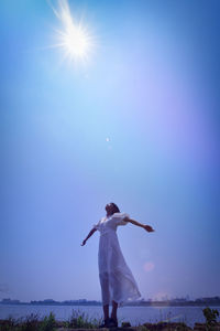 Rear view of woman standing against blue sky