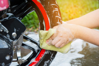 Cropped hands of woman washing motor scooter tire