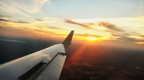 Close-up of airplane wing against sky during sunset