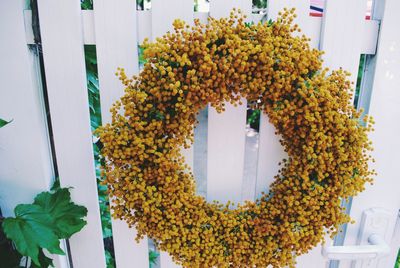 Yellow flower wreath on white fence