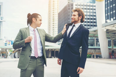 Businessman fighting with colleague on footpath against buildings in city