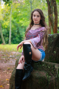 Portrait of beautiful young woman sitting on rock