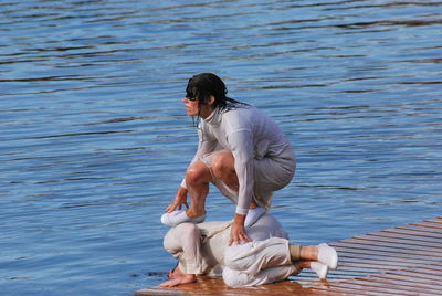 Woman crouching on friend against lake