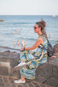 Young woman sitting on rock at beach