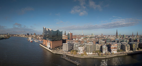 Buildings by river against sky in city