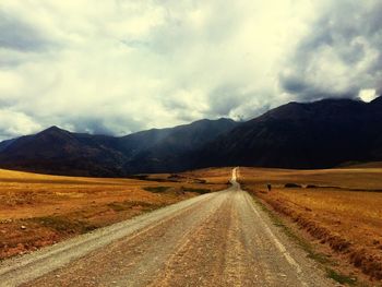 Country road against cloudy sky